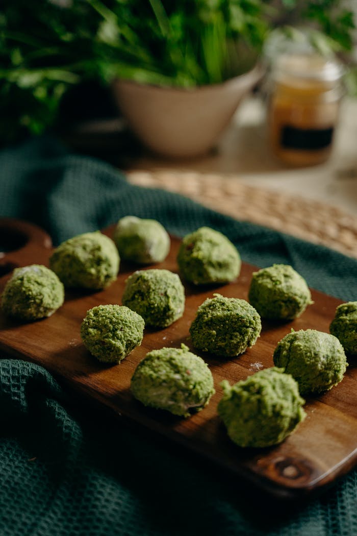 Freshly prepared green herb falafel on a wooden board, perfect for healthy vegan meals.
