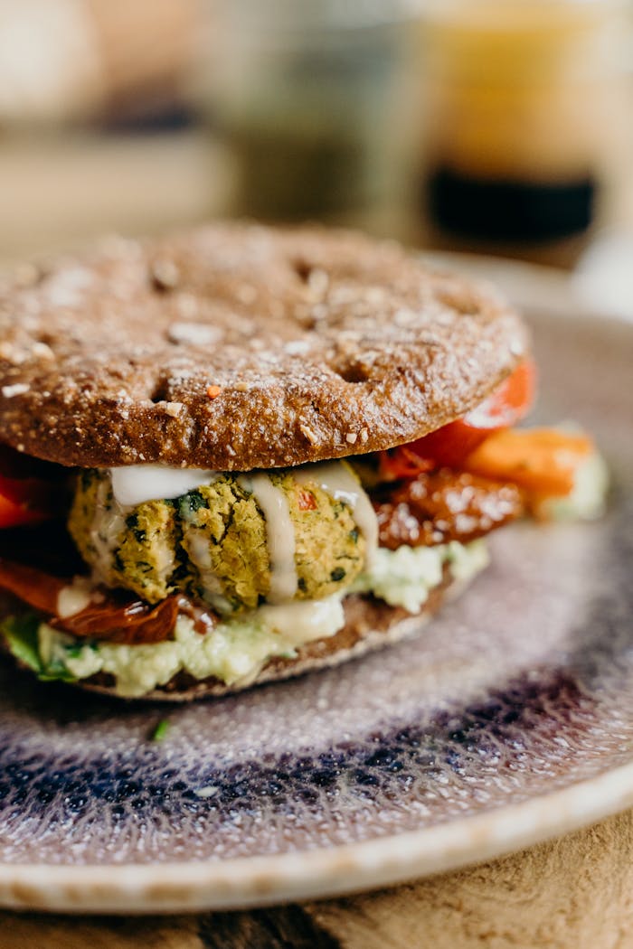 A close-up of a vegan burger with falafel and fresh vegetables, perfect for a healthy meal.